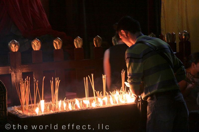 Chinese man lighting incense at Buddhist temple. Yangtzee RIver, China Chinese man lighting incense at Buddhist temple. Yangtzee RIver, China